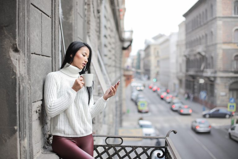 Mulher numa varanda a ver uma história de Instagram no seu telemóvel.