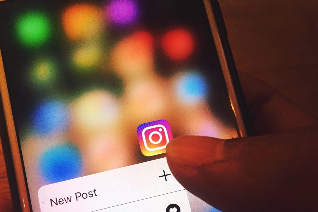 un dedo que señala una pantalla en la que aparece el icono de una aplicació Instagram 