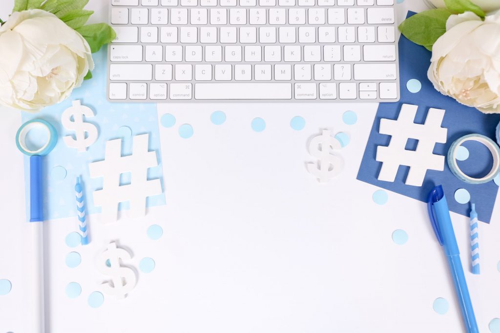 Un clavier sur le bureau avec diverses fournitures de bureau entourées de symboles hashtag et dollar.