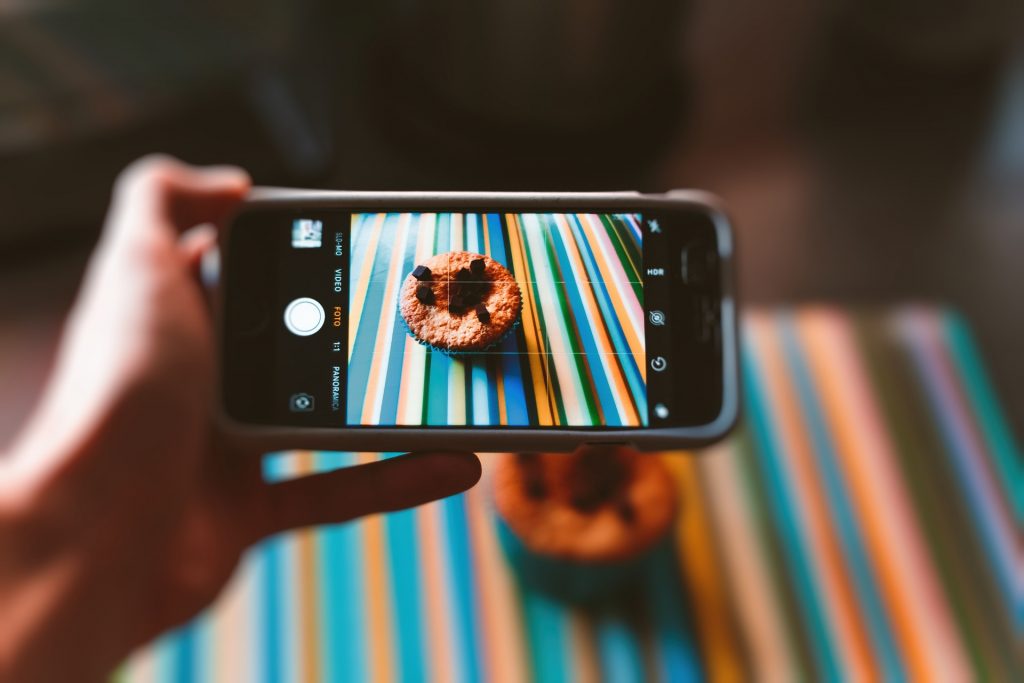A hand taking a picture of a cupcake