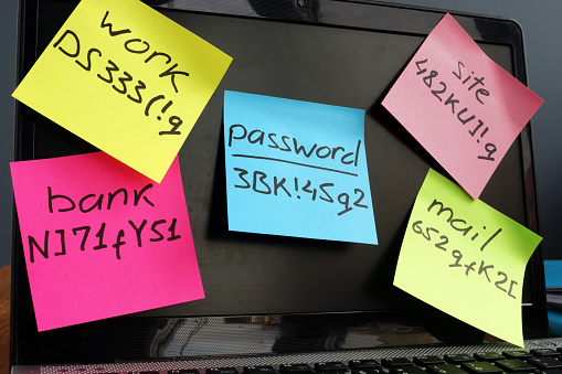Sticky notes with different passwords written on it, stuck on a computer monitor. 