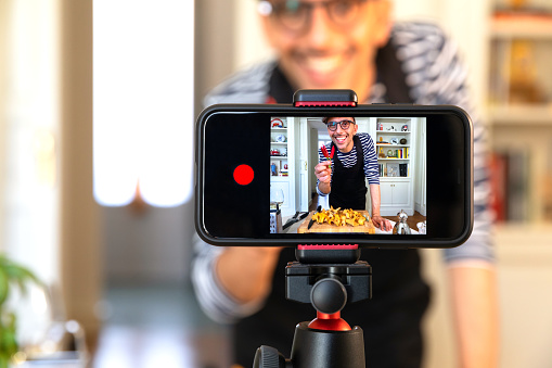 Vlogger standing in front of a phone camera and recording a video for an Instagram story.
