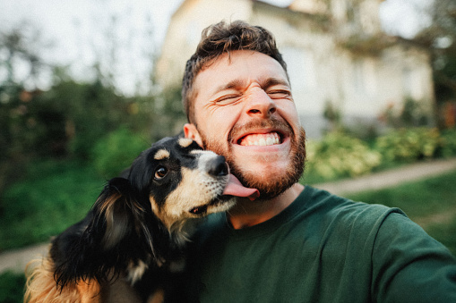 犬と一緒に外で自撮りする若い男性