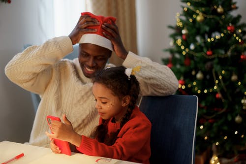 Pai e filha levando uma fotografia em frente da árvore de Natal