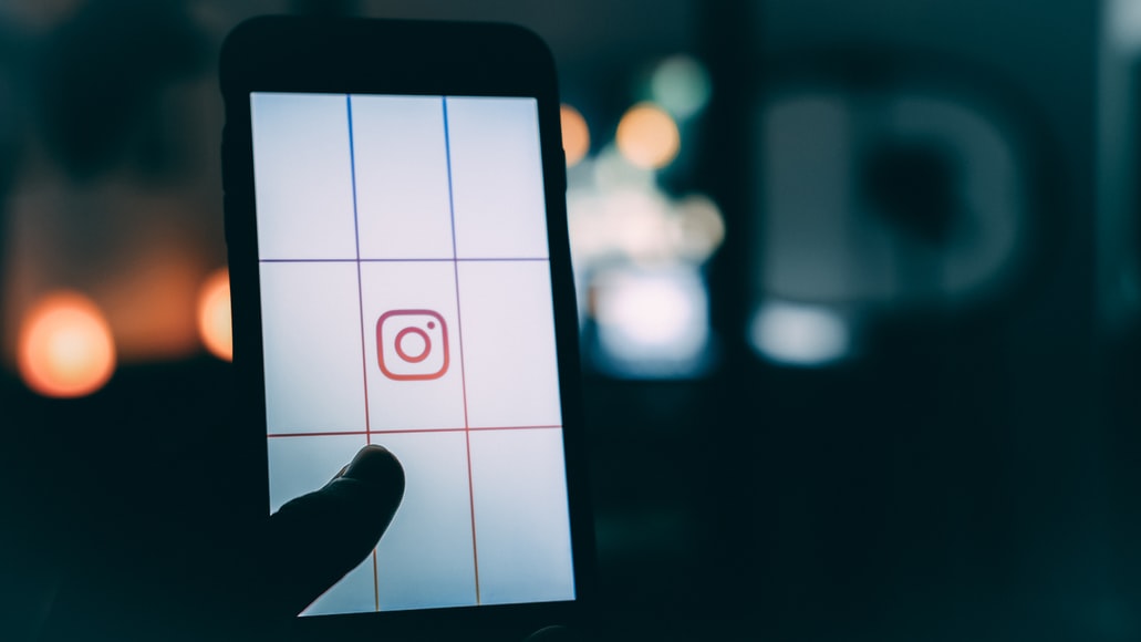 Instagram 로고가 있는 스마트폰을 사용하여 보케 사진을 촬영하는 사람.