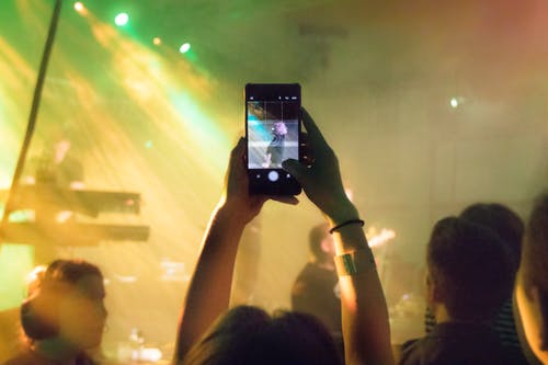 Person in a crowd at a concert taking an Instagram Story with music.