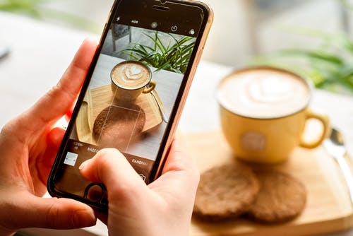 Person taking a photo of coffee and cookies for a scheduled Instagram post.