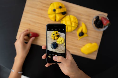 Person taking a high-quality photo of fruits to promote Instagram page organically.