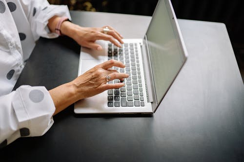 Vrouw typt commentaar op Instagram op een laptop.