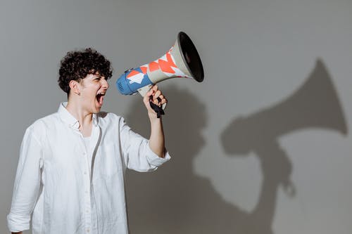 Hombre usando un megáfono para representar cómo promocionar tu página y contenido de Instagram. 