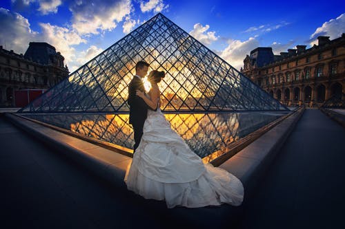 Hochzeitsfoto vor der Glaspyramide des Louvre-Museums zum Posten auf Instagram mit einem personalisierten Hochzeits-Hashtag.