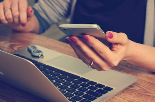 Een vrouw maakt interessante Instagram content met een laptop en telefoon. 