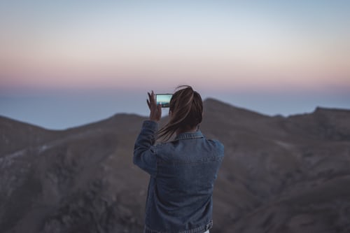 Woman taking a photo of mountains to create engaging content for Instagram. 