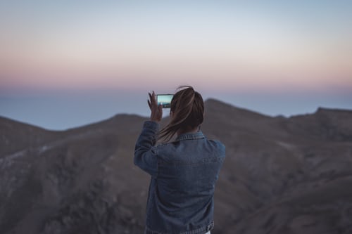 Mujer fotografiando montañas para crear contenidos atractivos para Instagram. 