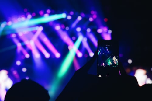 A person taking a photo of a live concert to create content for Instagram Stories. 