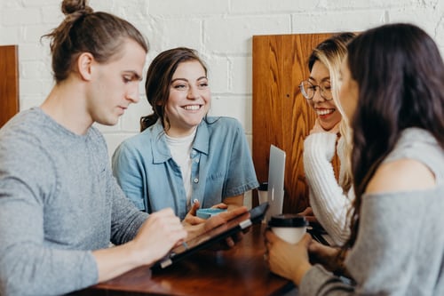 A group of people working on the laptops and tablets and discussing ways to increase engagement on Instagram. 