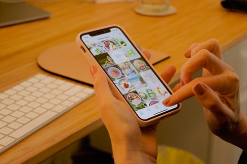 A woman browsing through photos on a phone and figuring out how to delete an Instagram post.