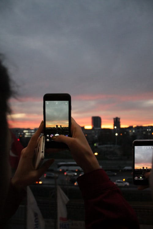 Iemand met een mobiele telefoon die een film maakt en op Instagram zet.