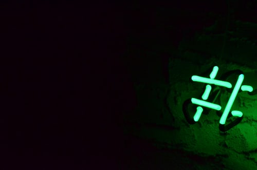 Neon light hashtag symbol on wall.