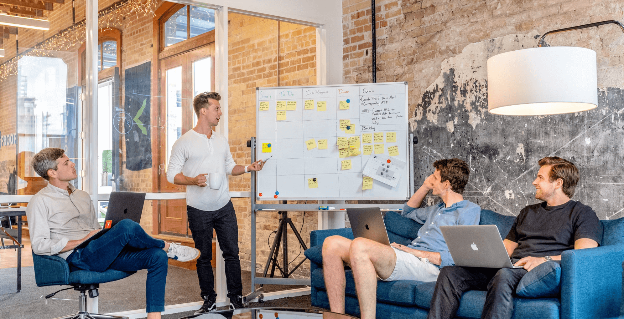 a man standing in front of a whiteboard with sticky notes on it