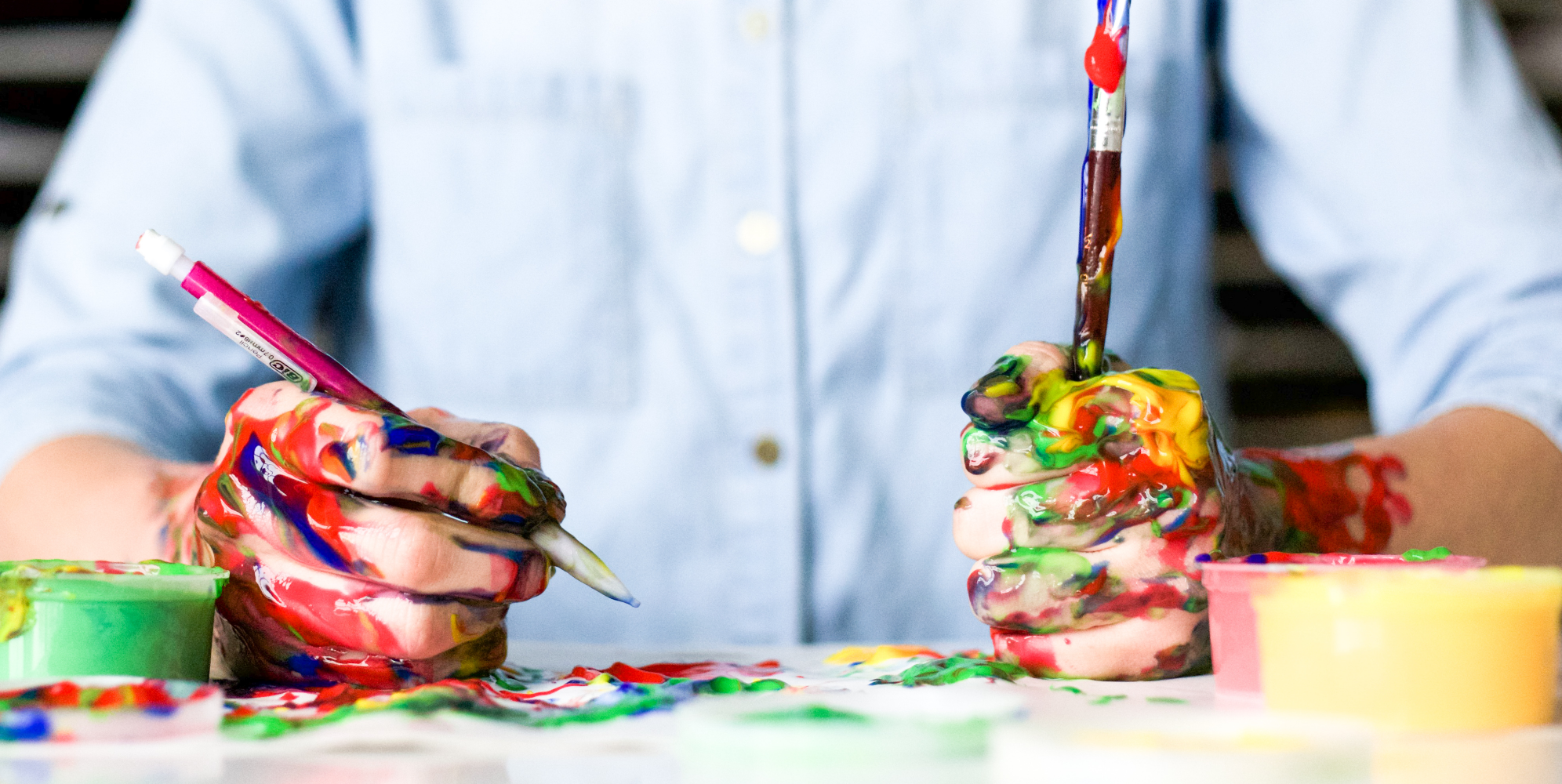 Una persona pintando para cultivar su arte en Instagram, con las manos cubiertas de diferentes colores de pintura.