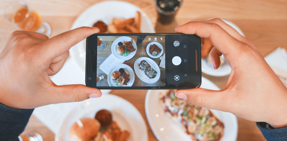 hands holding a phone taking a picture of food