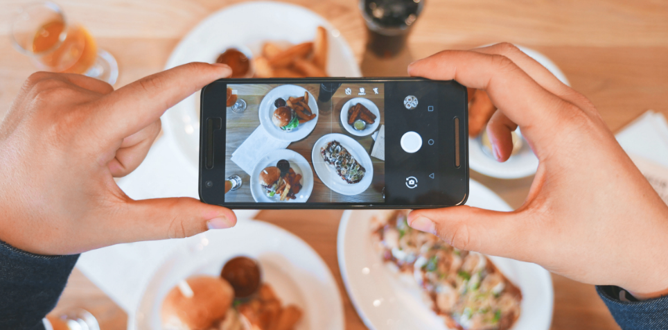ig-food-account-img1 | Path Social mãos a segurar um telemóvel para tirar uma fotografia de comida
