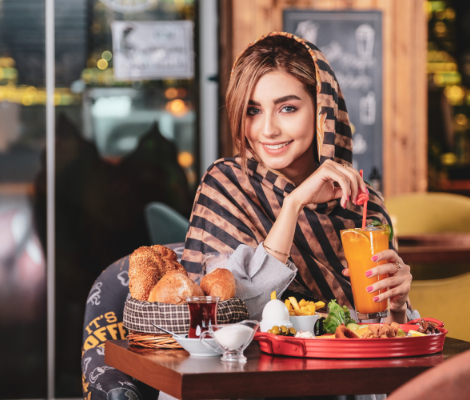 a woman sitting at a table with food and drink