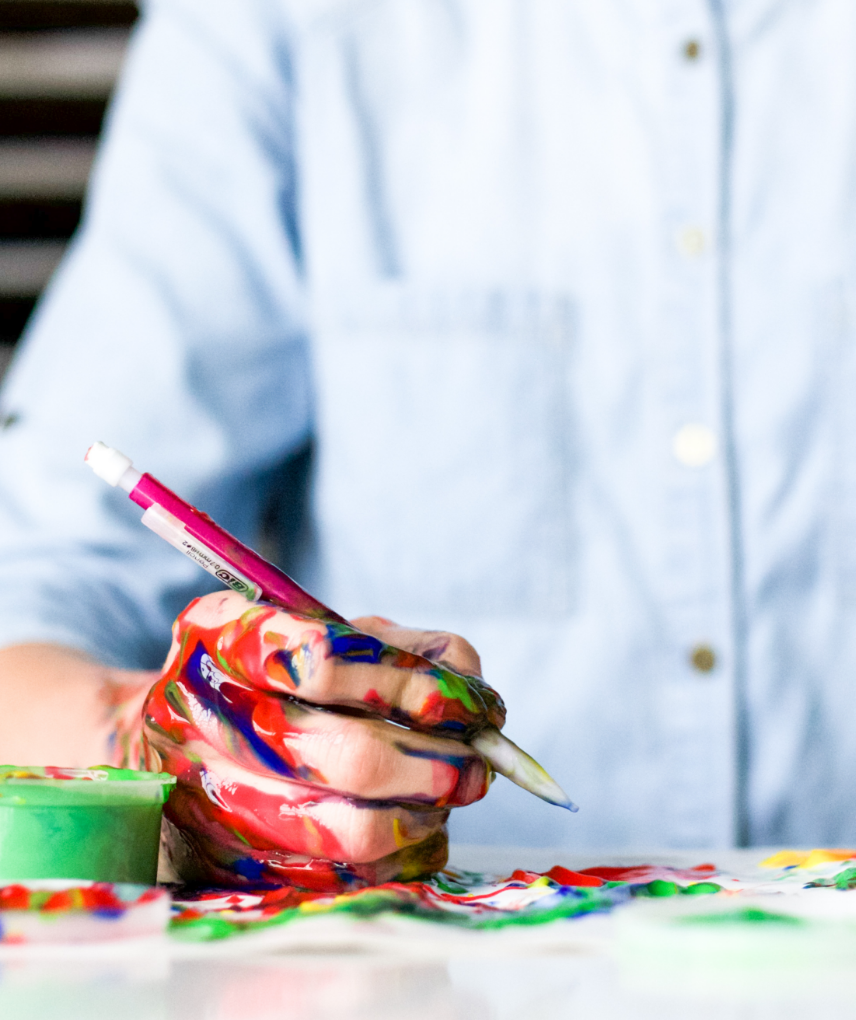 a person holding a paintbrush and paint on a table