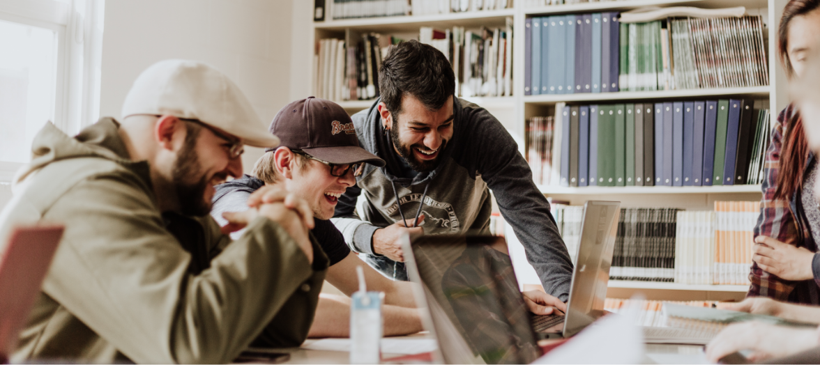 a group of men looking at a laptop