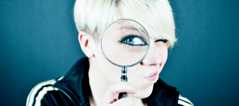 Woman looking through a magnifying glass demonstrating how to check Instagram growth