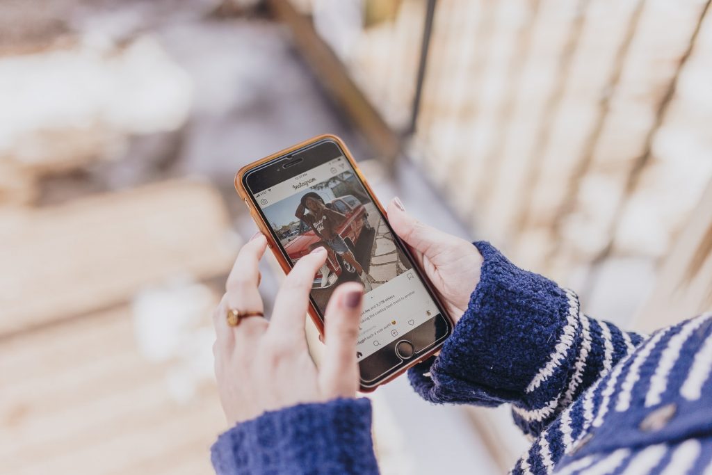 Una mujer que sostiene un teléfono en el que se ve una publicación de « instagram » abierta.