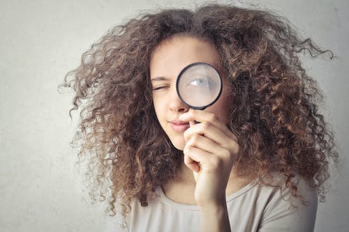 Una chica con una lupa en el ojo para demostrar cómo aparecer en la página Explorar de Instagram. 