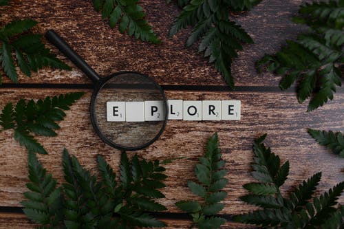 Magnifying glass on top of letter tiles spelling “Explore” to represent how to get on the Instagram Explore page.