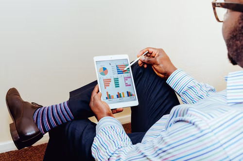 Ein Mann hält ein Tablet in der Hand und studiert Diagramme, die die Leistung von gepushten Instagram Stellen zeigen. 