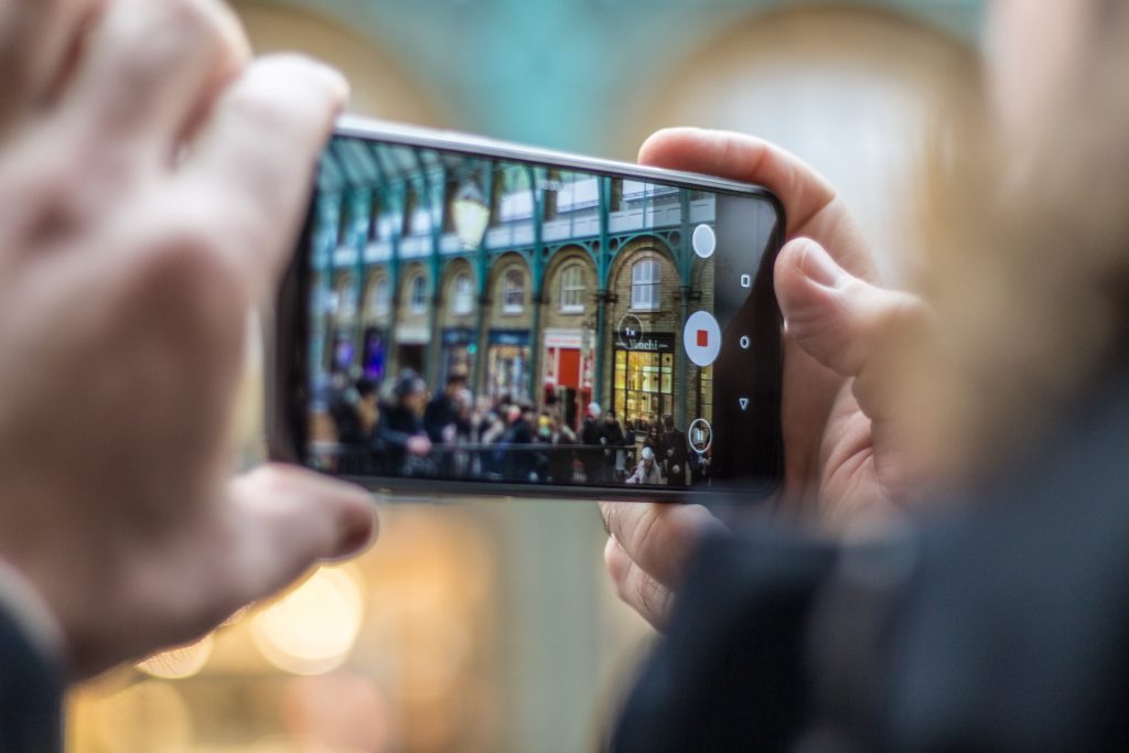 A person holding smartphone taking video of people.