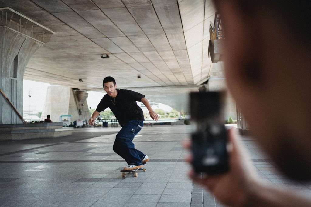 Person taking a photo of a skateboarder on a smartphone to learn how to make a reel on Instagram.