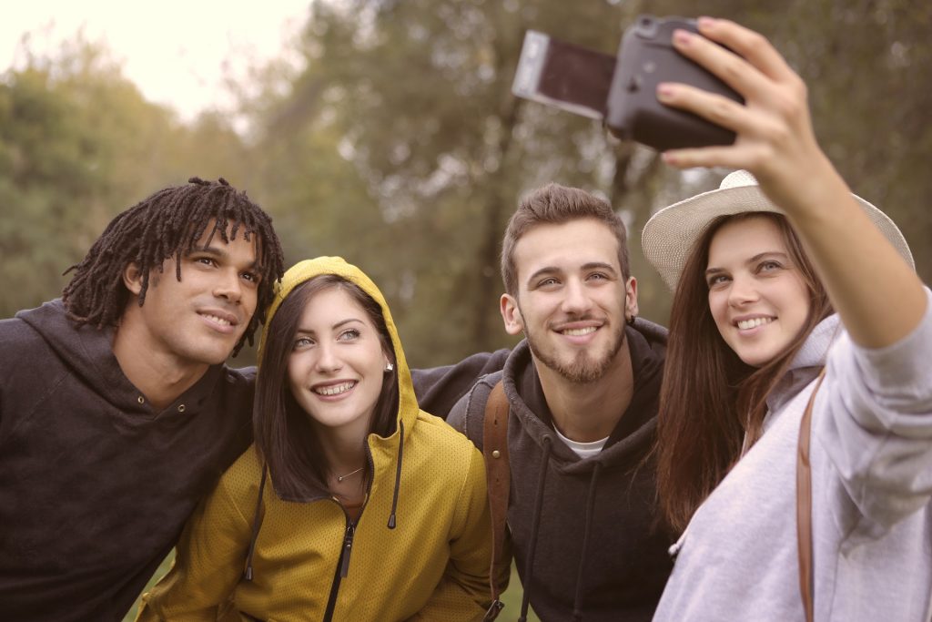 Group of people taking a selfie outdoors to use when learning how to repost a story in Instagram.
