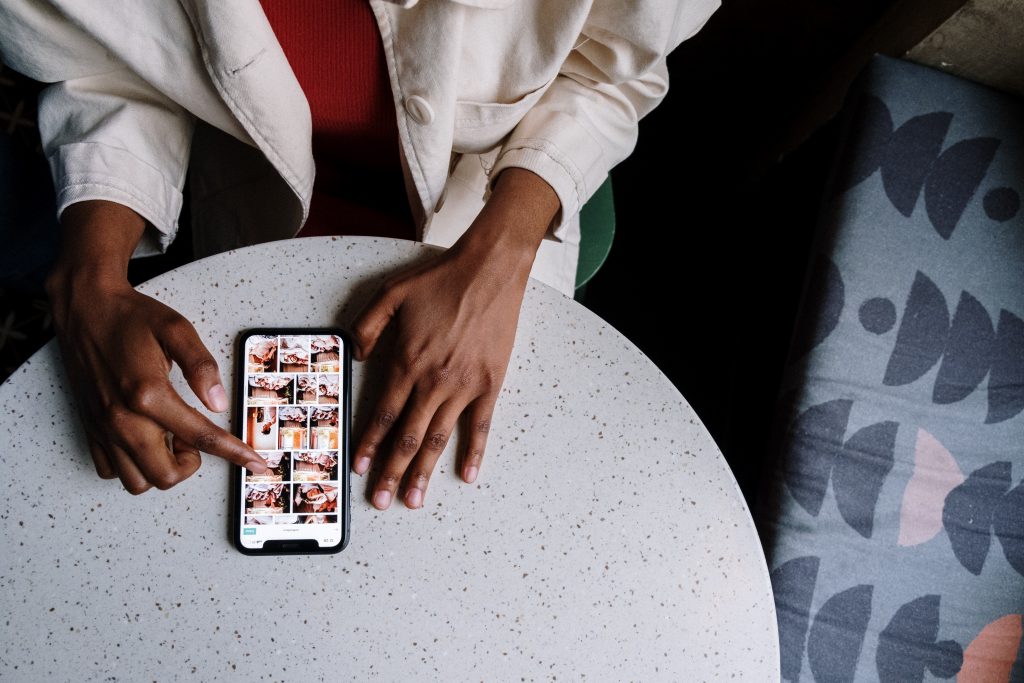 Person in white jacket using smartphone that is open to Instagram.