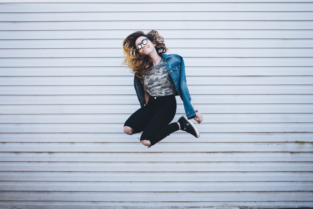 A woman wearing sunglasses jumping isolated.