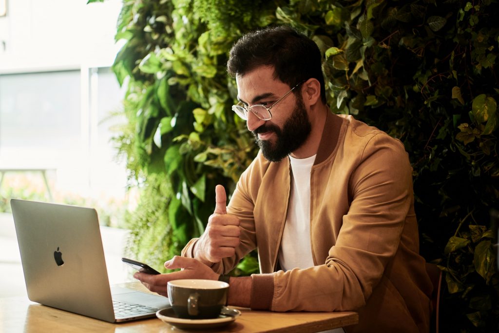 Woman holding a phone and sitting in front of a laptop doing a Live Q&A on Instagram.