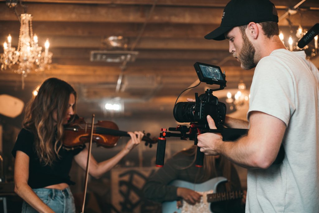 Uomo che riprende una ragazza che suona il violino per un evento di Instagram . 