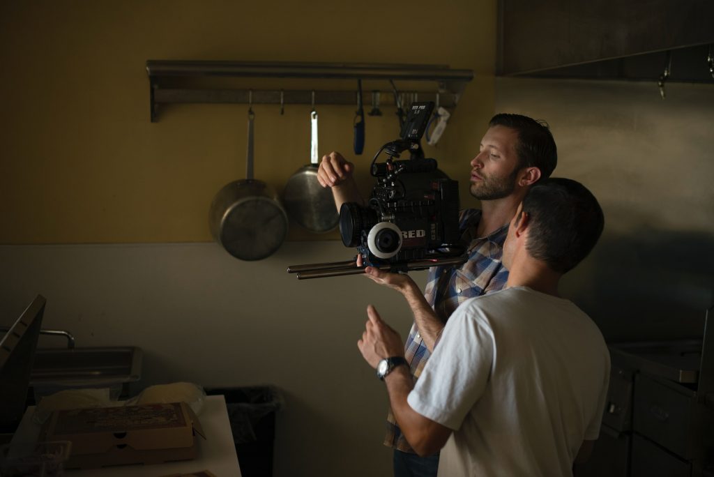 Two men fixing camera inside kitchen.
