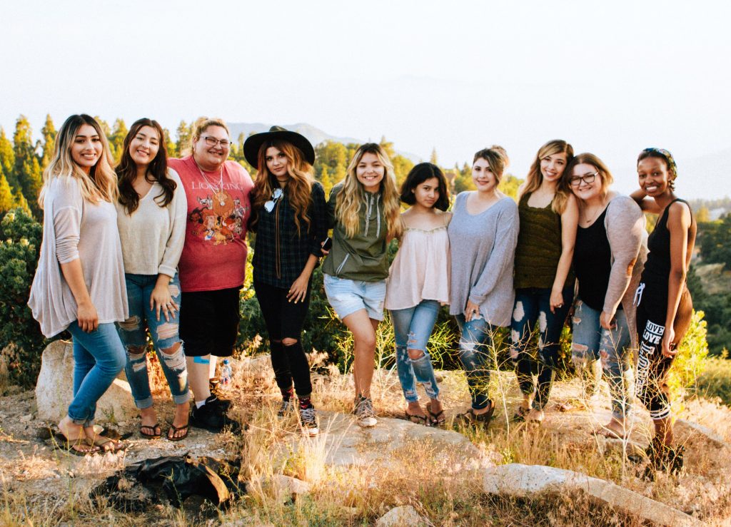 Um grupo de mulheres a posar para uma fotografia no cimo de uma colina para serem marcadas várias vezes no Instagram. 