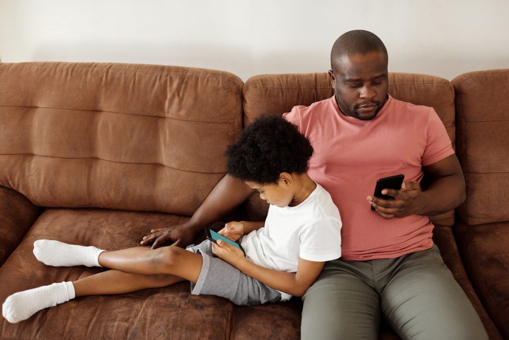 Image of a father and his son who are on their phones playing Instagram games.