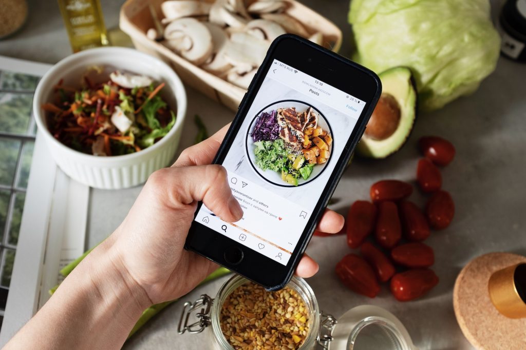 A person holding black smartphone taking photos of food.