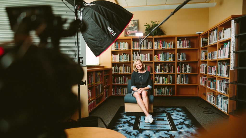 Woman sitting in front of a camera in a bookstore and doing an Instagram takeover. 