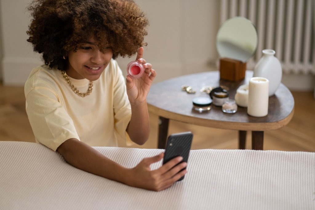 uma mulher a segurar um telemóvel e a maquilhar-se