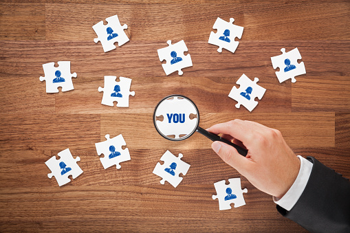 istockphoto-612014554-170667a-1 | Path Social Image d'une main d'homme tenant une loupe, regardant des pièces de puzzle, en particulier une pièce avec le mot YOU.