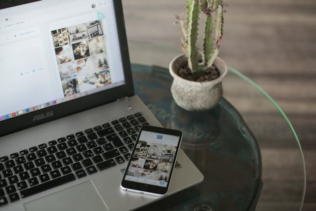 pexels-plann-2999237-4565775 | Path Social Laptop argintiu și smartphone negru pe o masă de sticlă cu o plantă lângă ele.